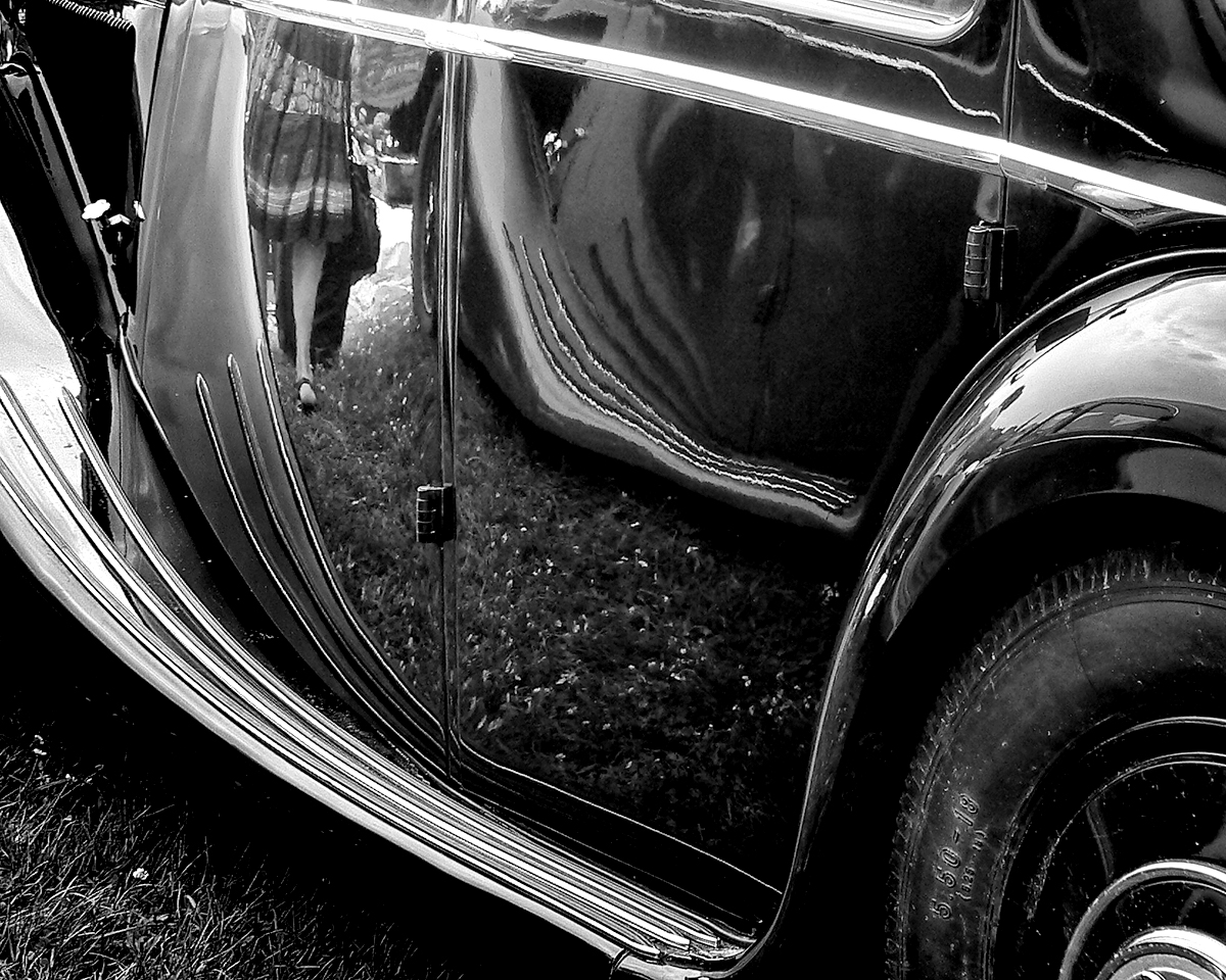 Reflet de jupe et pâquerettes sur carrosserie rutilante de voiture ancienne